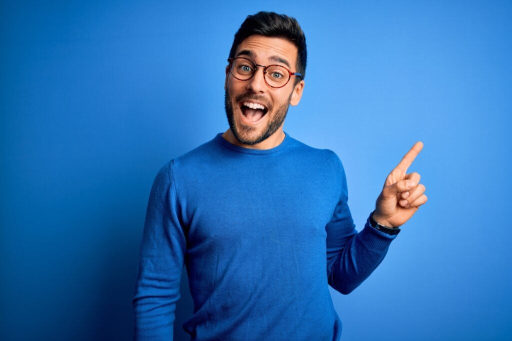 Man wearing casual sweater standing in front of a blue wall