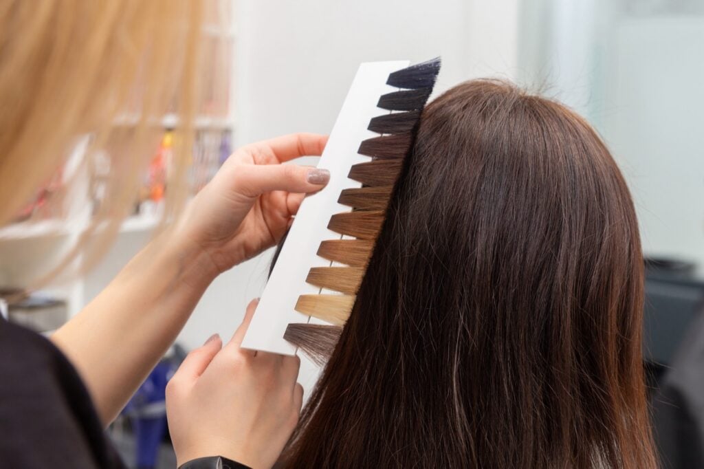 Hairdresser selecting dye color using palette of common hair colors