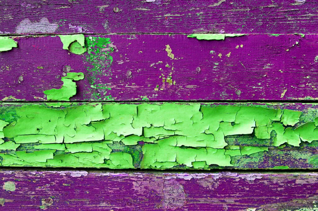 Textured wooden background with green and violet peeling paint.