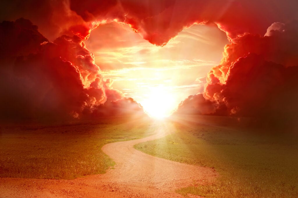 Red heart shaped sky at sunset with a road leading to the heart.