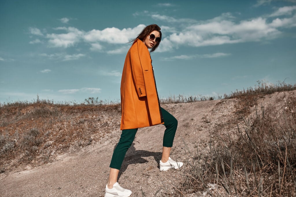 Woman outside wearing burnt orange coat and black pants.