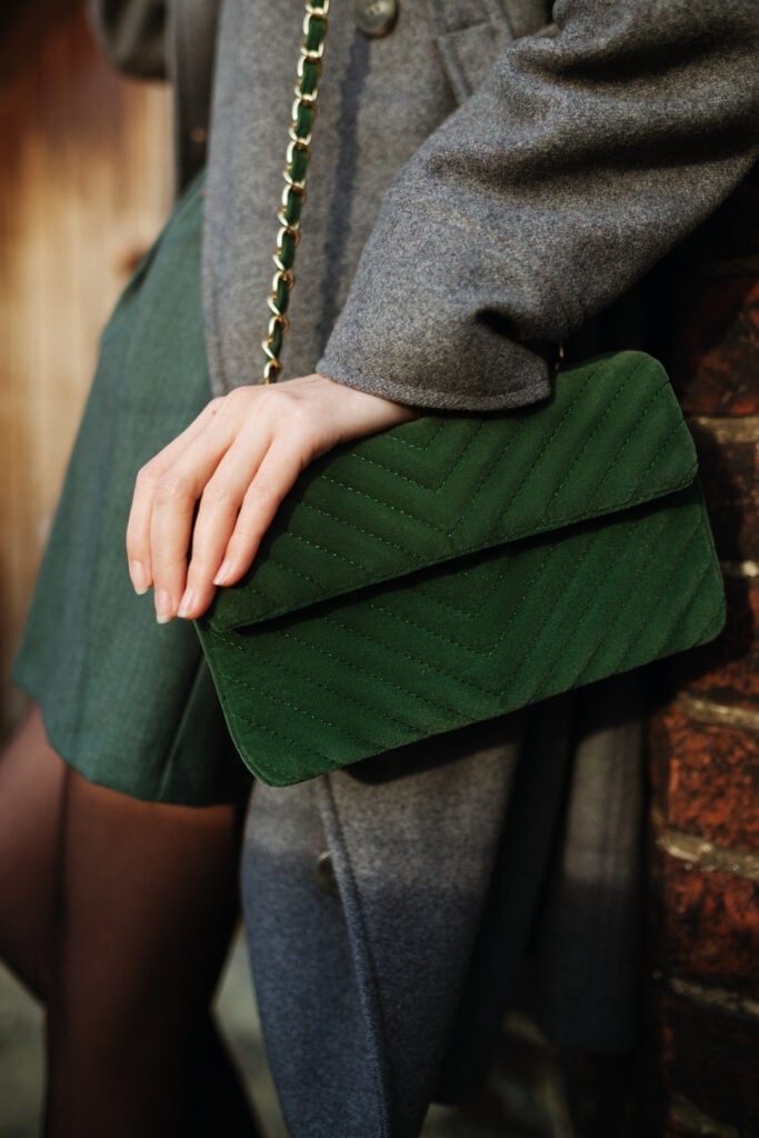 Woman with dark green handbag and gray coat.