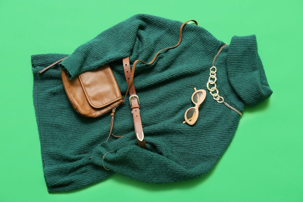 Stylish green sweater and accessories on green background.