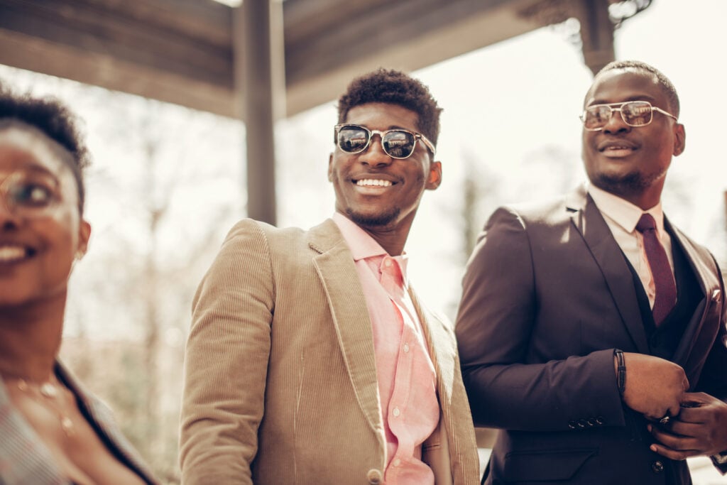 Two guys at a wedding, one wearing a tan suit.