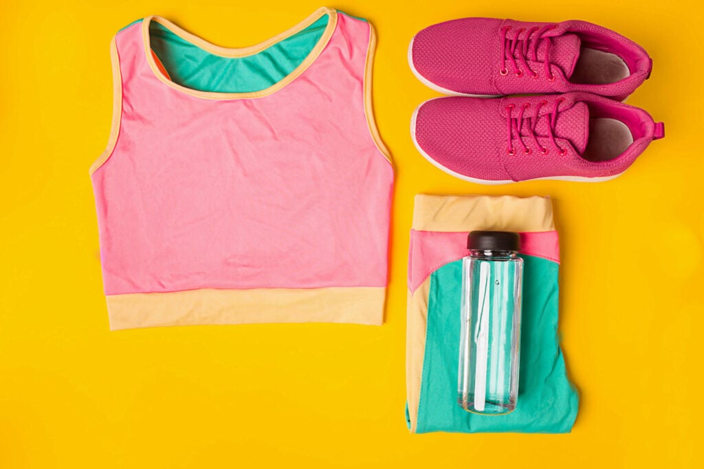 Sneakers and bottle of water on yellow background.