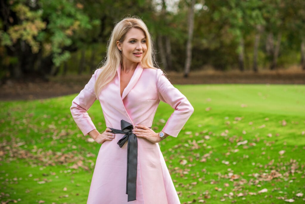 Woman in pink dress posing in grass. 