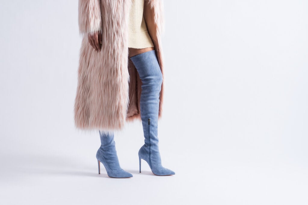 Model posing with fancy coat and long boots.