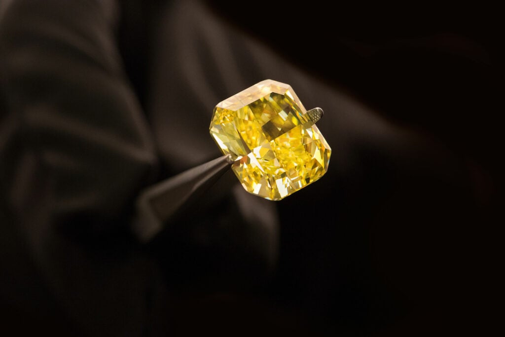 Yellow diamond held by tweezers