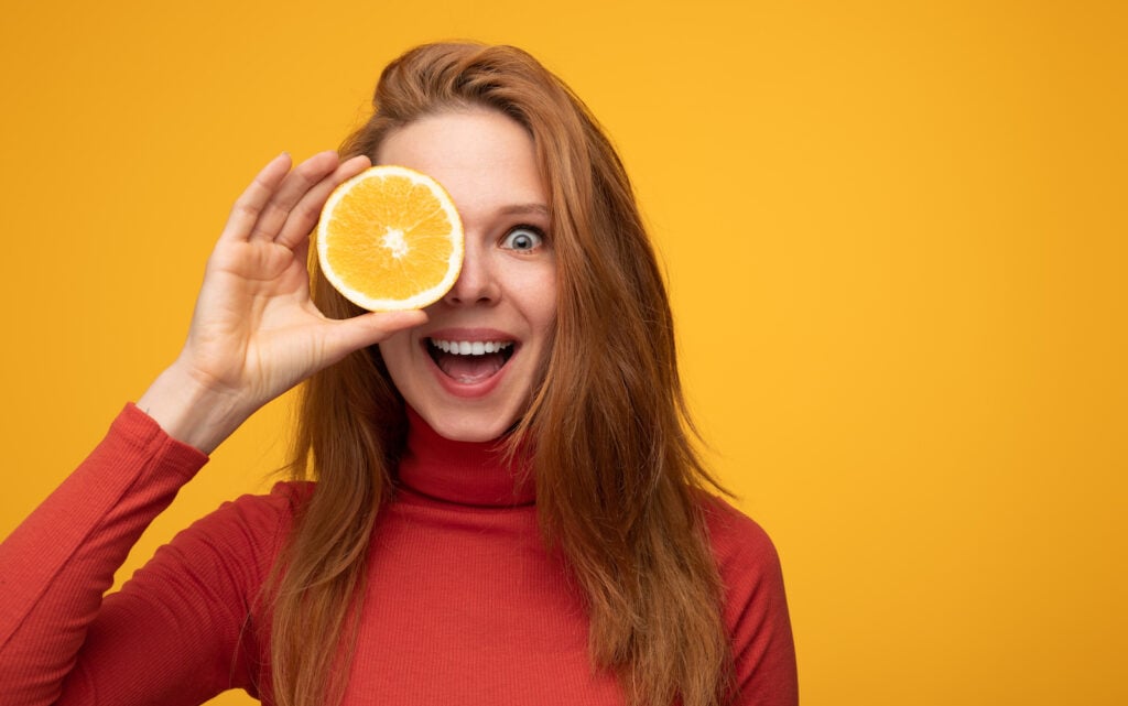 Lady holding an orange in front of her eye