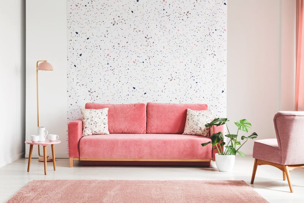 Photo of a pink, velvet sofa, plant, and coffee table.