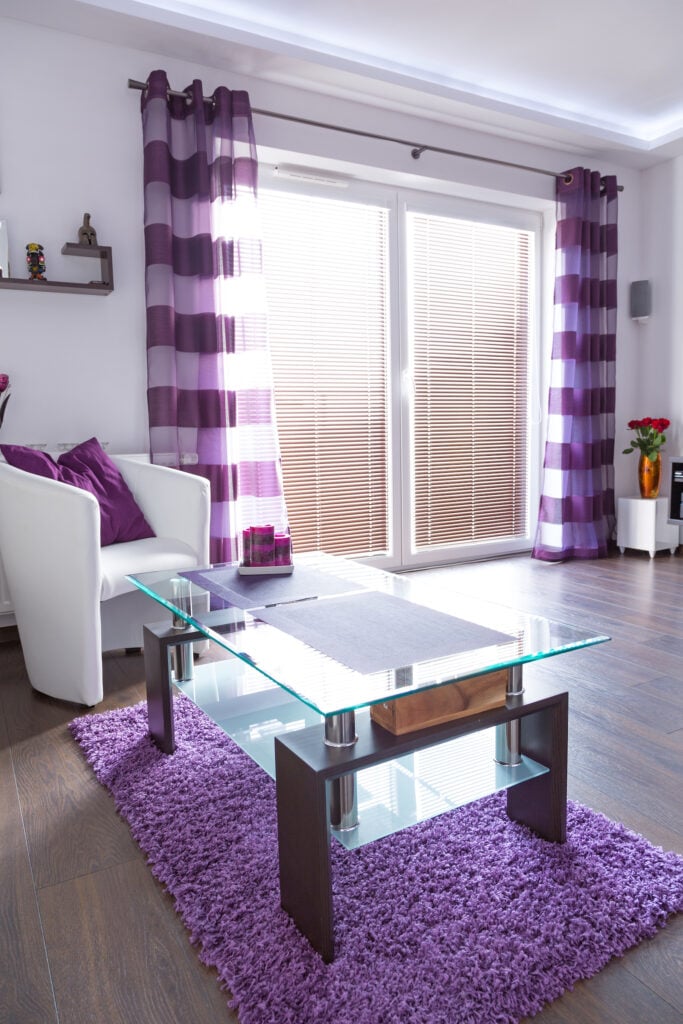 Modern white living room interior with purple decorations.