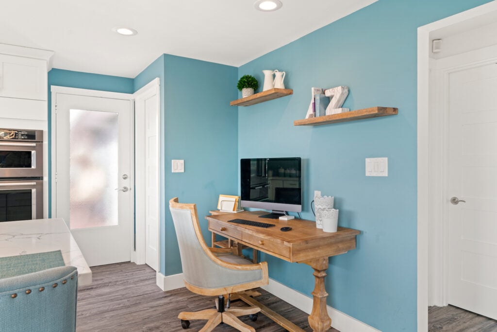 Home office space with wooden table and blue painted wall.