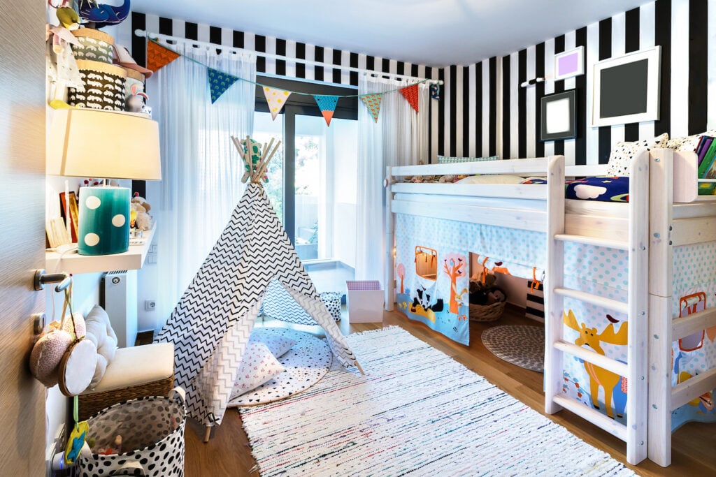 Kids bedroom with bunk bed and black and white stripes on wall.