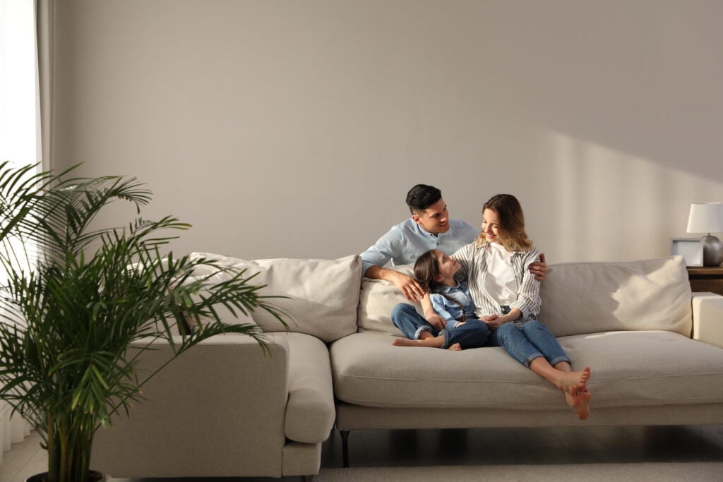 Family with little daughter on sofa in cool beige living room.