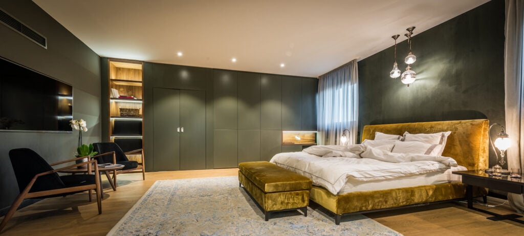Master bedroom interior with dark walls with mustard yellow furniture.