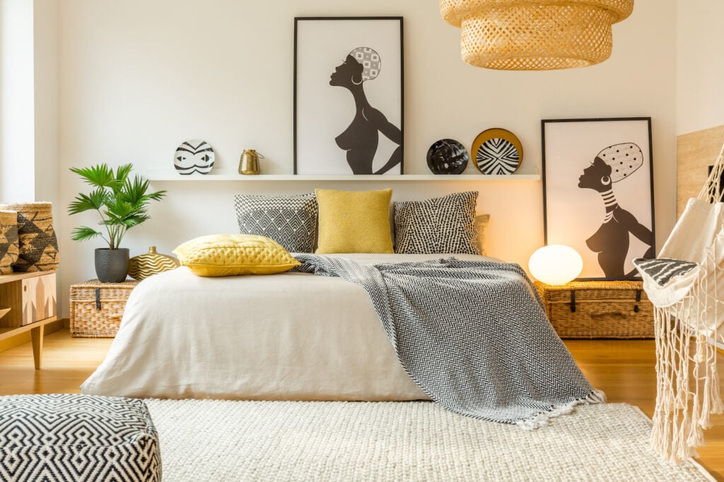Yellow and patterned pillows on bed in modern warm white bedroom.