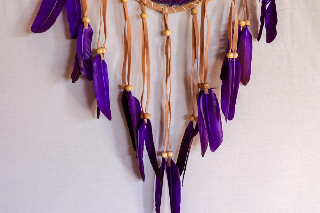 Closeup of modern dreamcatcher with purple feathers.