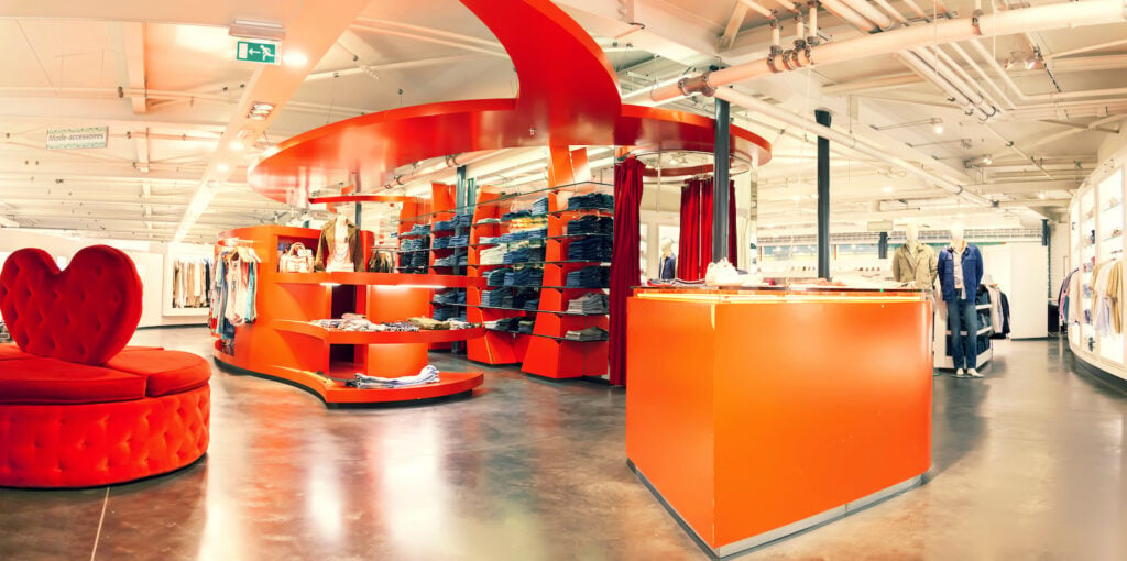 Interior of unique clothing store in warehouse with bright red and orange displays