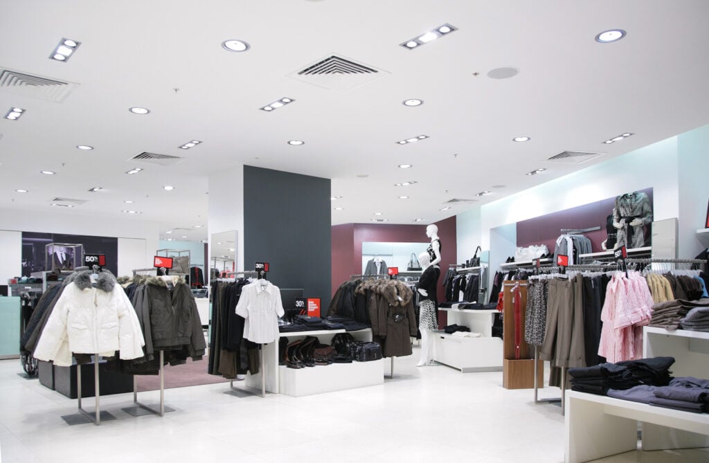 Department store interior with winter coats, white floors, and burgundy accent walls