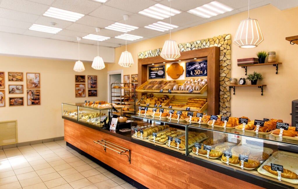 Interior of Russian bakery with pastries in glass display cases and soft pastel yellow walls