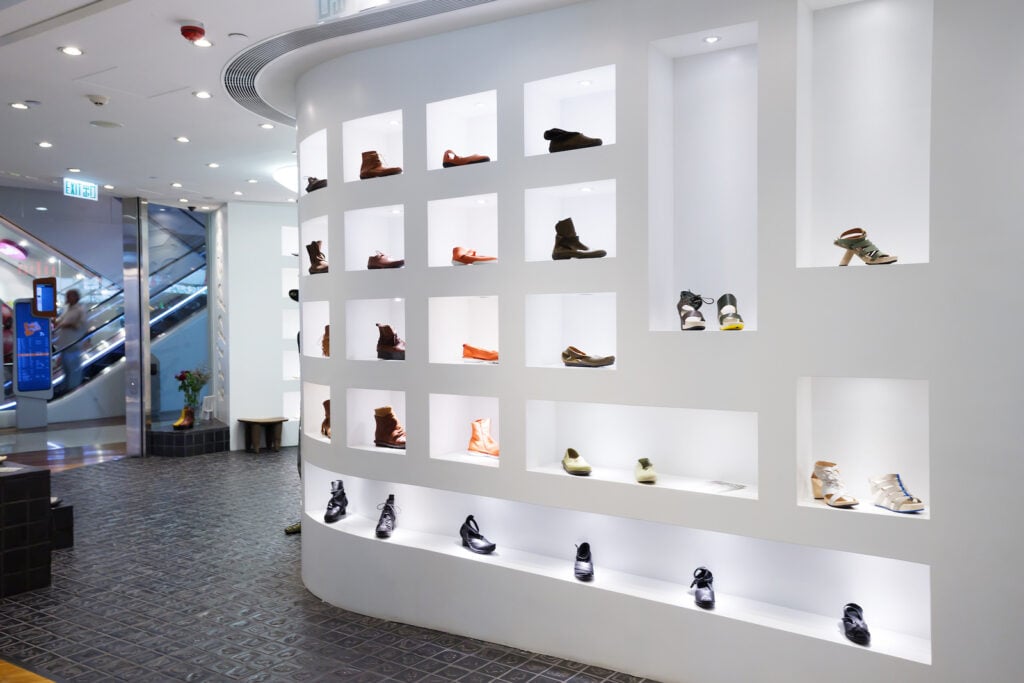 Interior of modern shoe designer store with minimalist white shelving