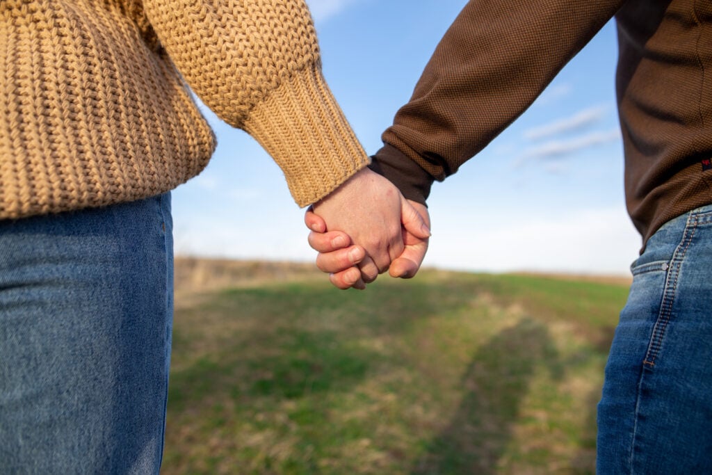 Couple wearing tan and brown clothes holding hands outside