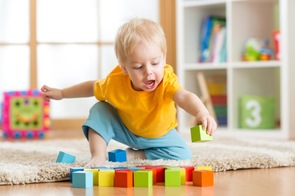 Kid plays with colorful wooden blocks