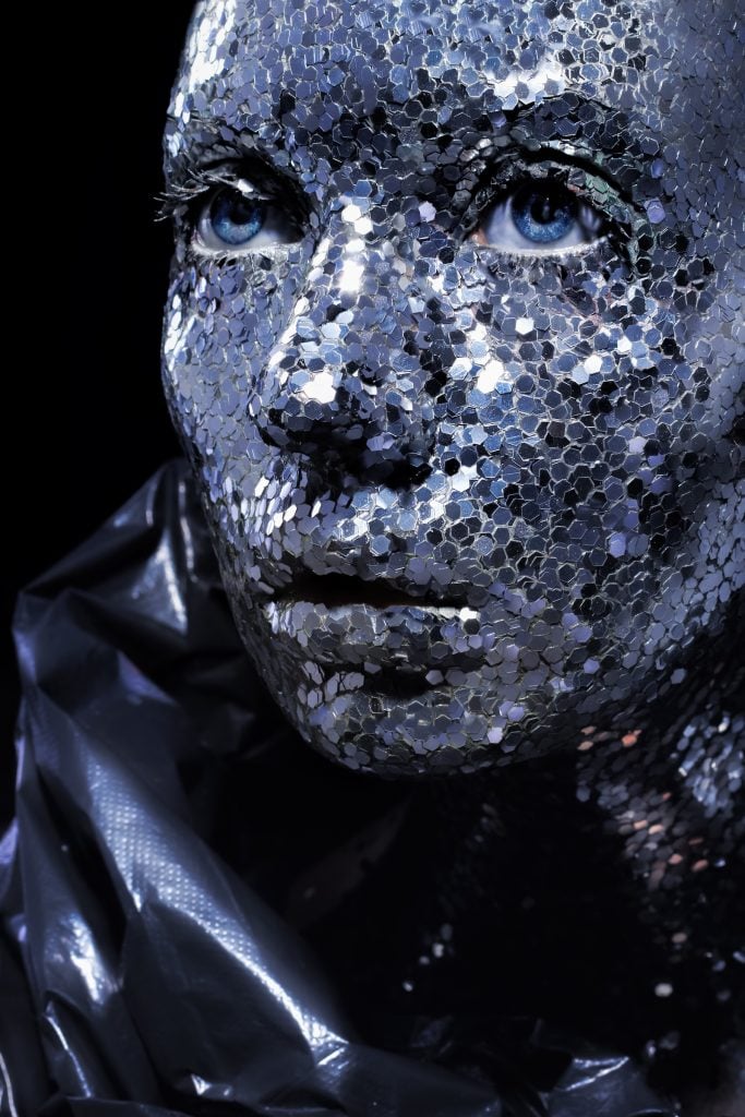 A close-up shot of a woman whose face is covered in silver sequins