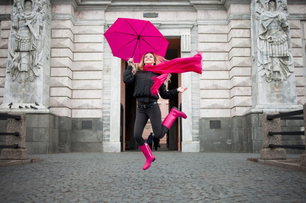 Happy woman with colorful magenta umbrella on the street
