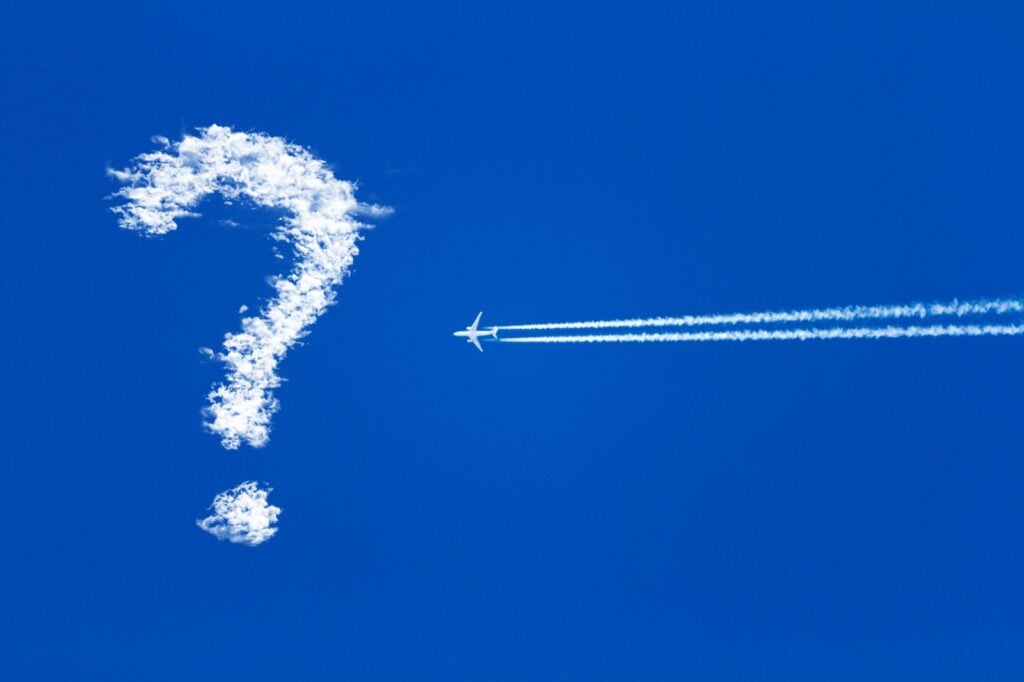 A blue sky with a question mark and an airplane flying toward it