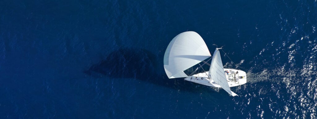 Image of an all-white sailboat floating on the deep blue Mediterranean Sea