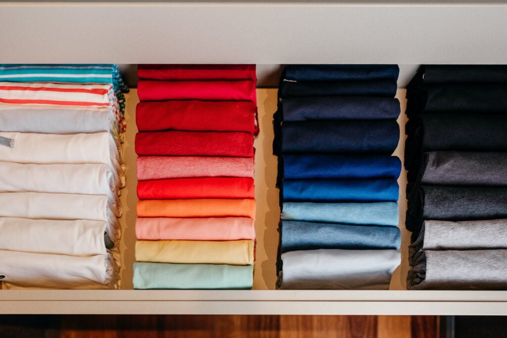 A highly-organized drawer of shirts folded and arranged by color