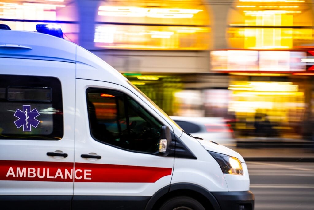White ambulance driving quickly in city