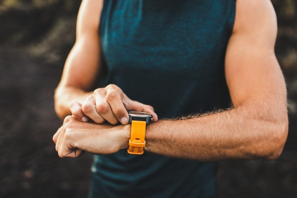 Homme aventureux avec montre intelligente orange faisant de l'exercice à l'extérieur