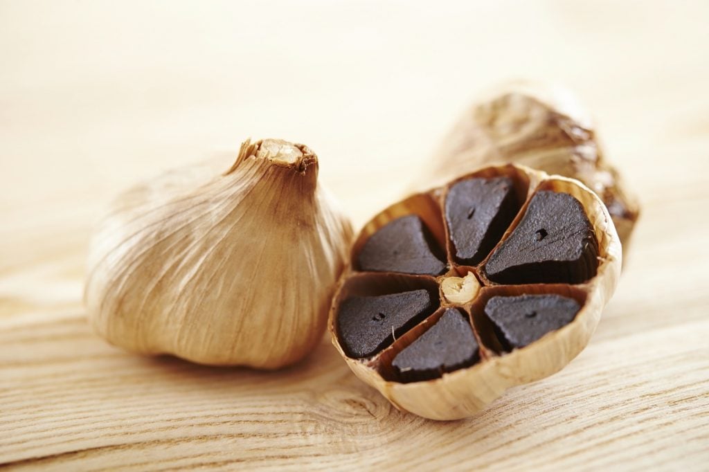 Black garlic cloves on wooden table