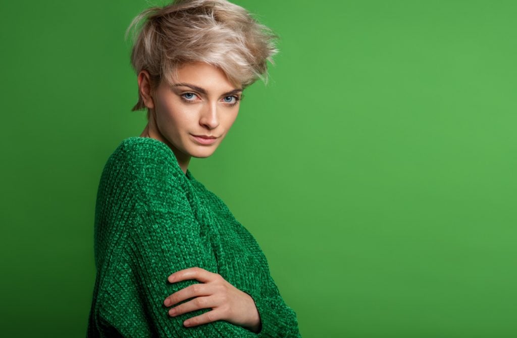 Fashion portrait of woman with blond short hair wearing green sweater
