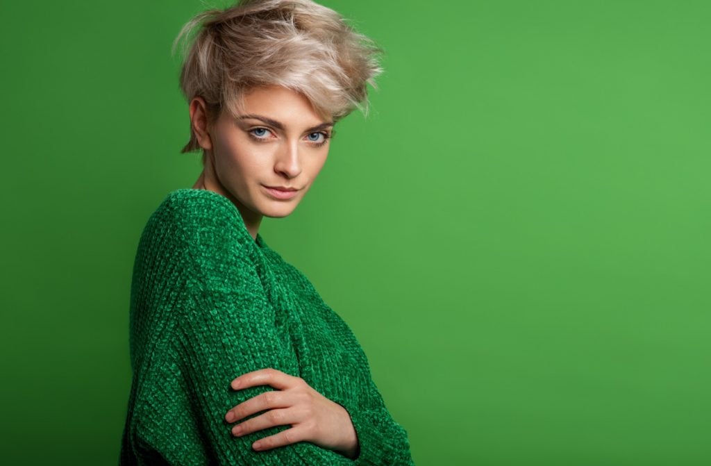 Portrait de mode d'une femme aux cheveux courts blonds portant un pull vert