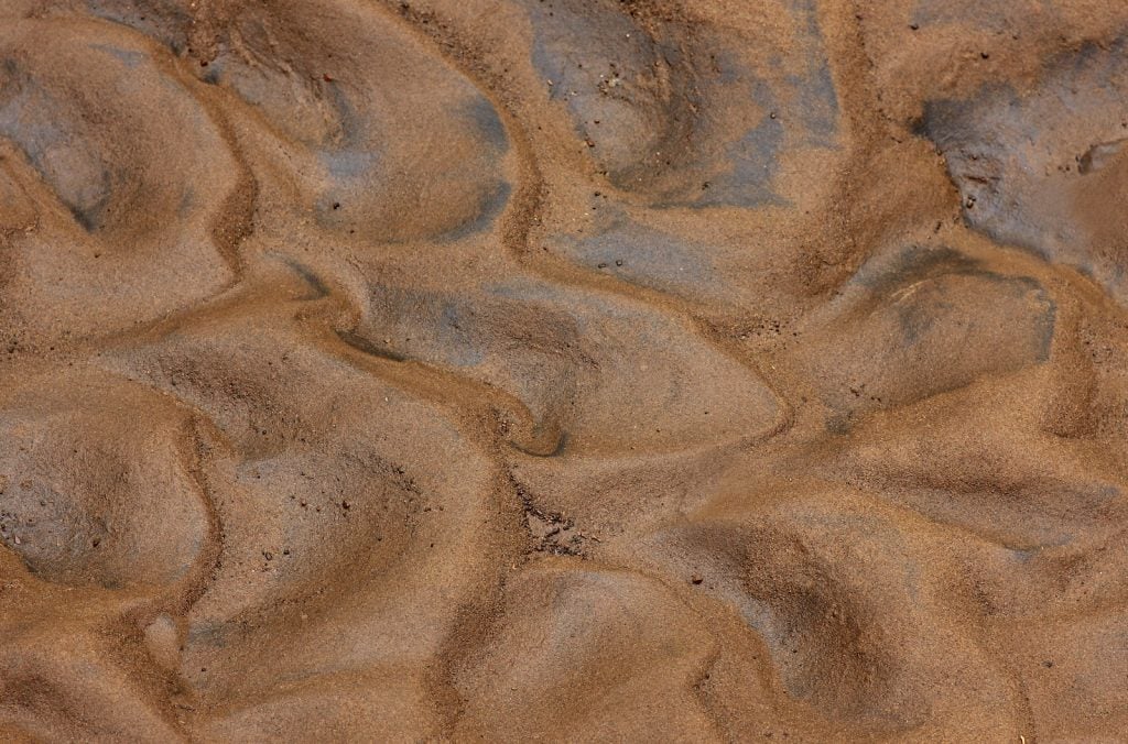 Close up of wet brown sandy silt in former riverbed