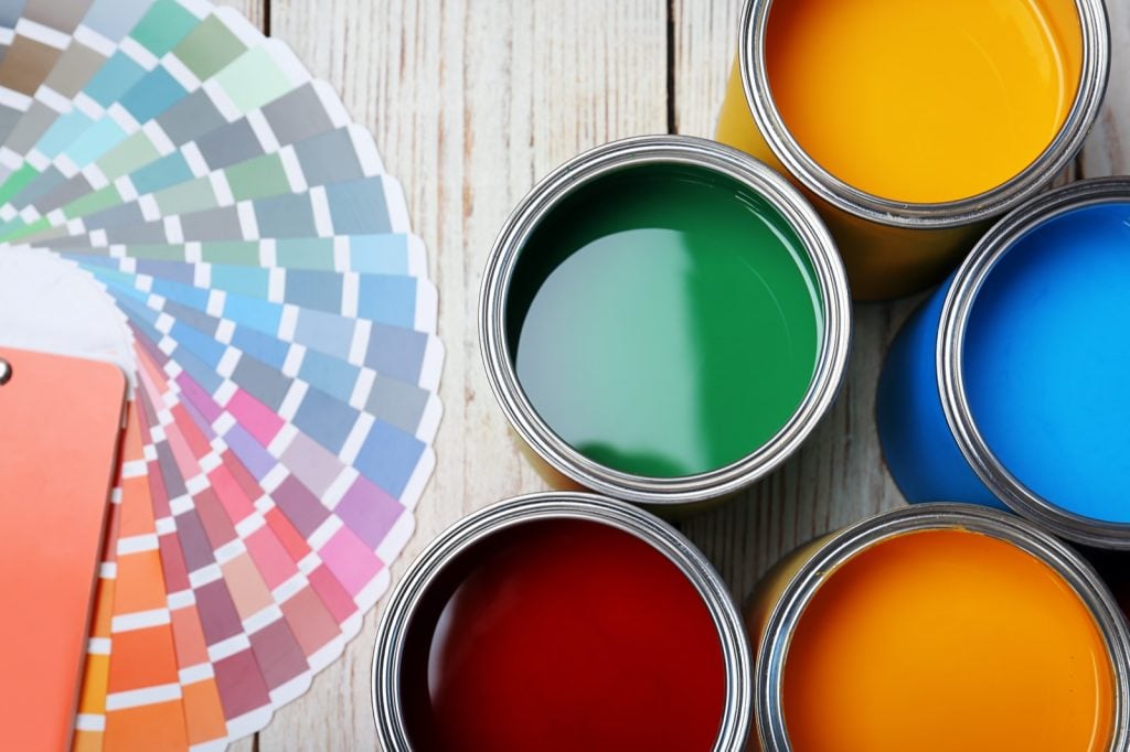 Top view of cans with paint and color palette on wooden background
