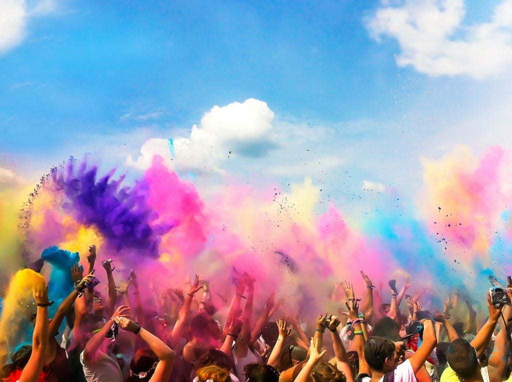 Crowd of people throwing colored powder in the air at Holi festival