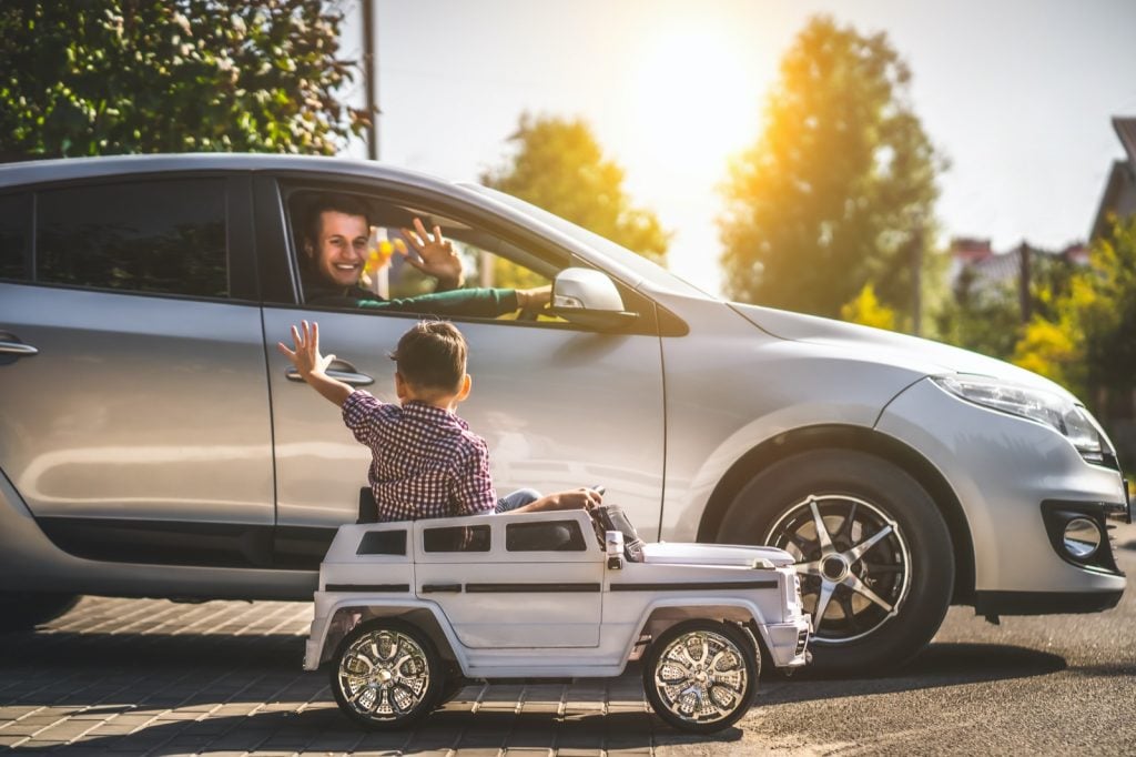  Père dans sa voiture en argent et son petit fils au volant d'une petite voiture jouet en argent 