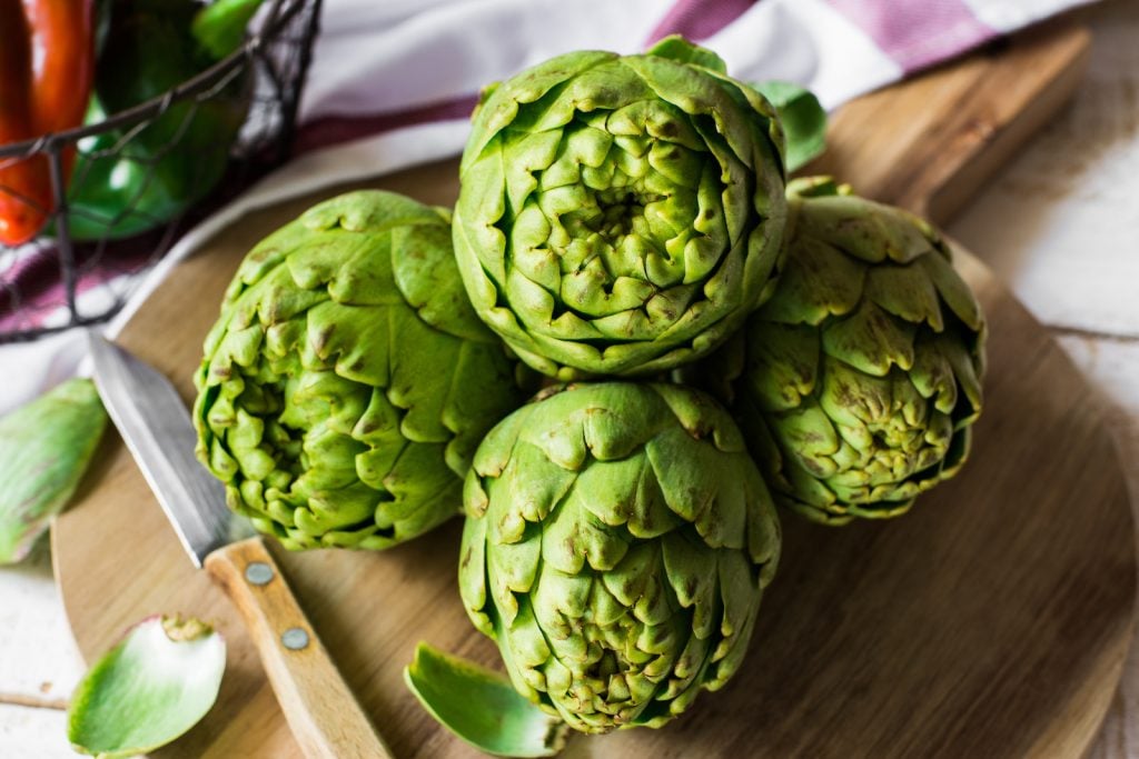 Fresh green artichokes on cutting board