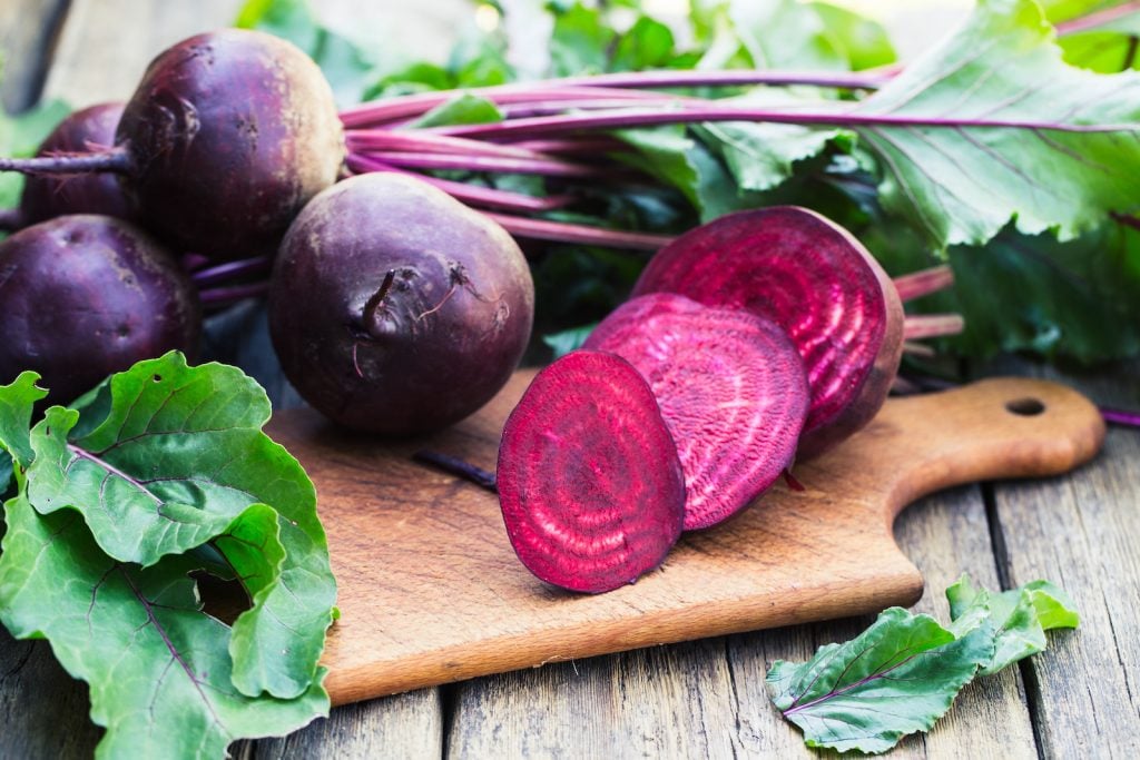 Fresh beetroots on a wooden chopping board one is cut in fine slices