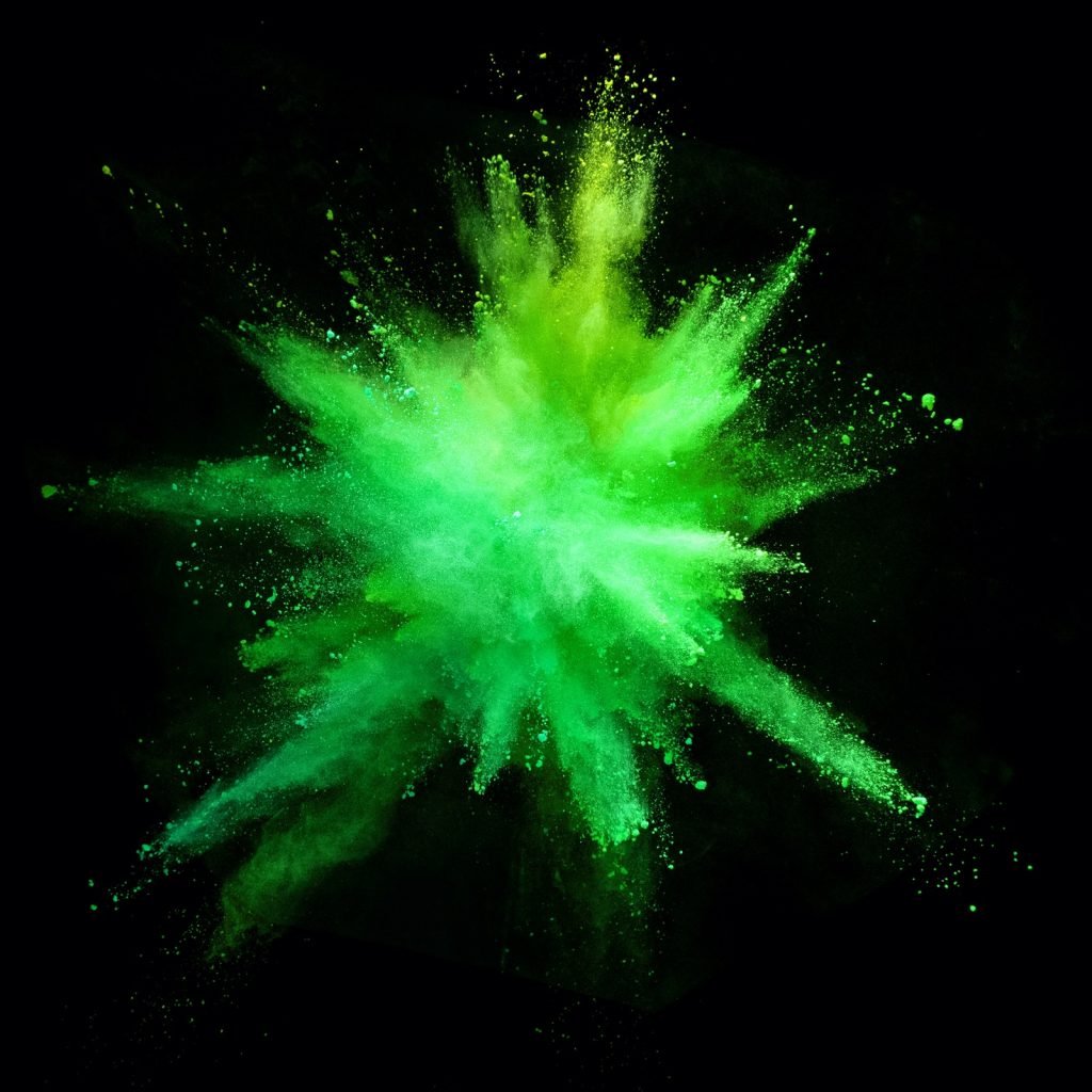 Explosion of green colored powder isolated on black background