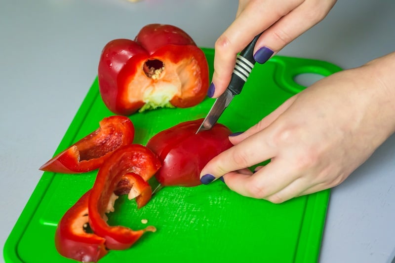 bell peppers being chopped on green cutting board