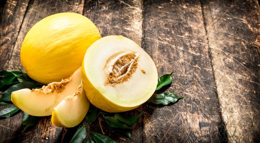 Sliced fresh honeydew melon on a old wooden table