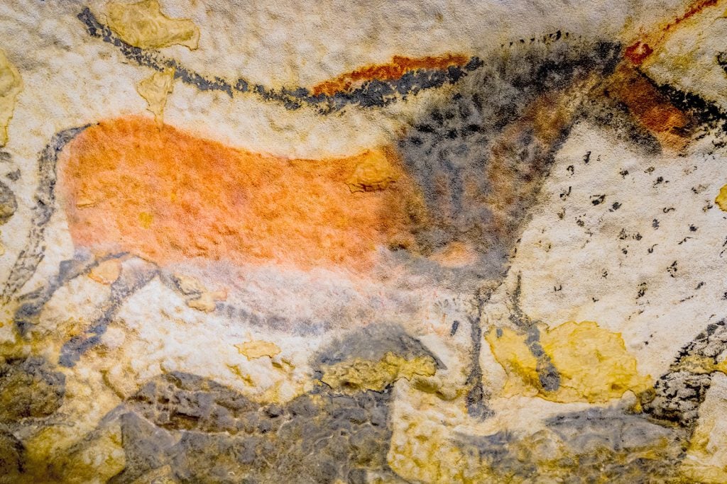 Horse painting with orange, yellow, and gray colors in the Lascaux caves in France
