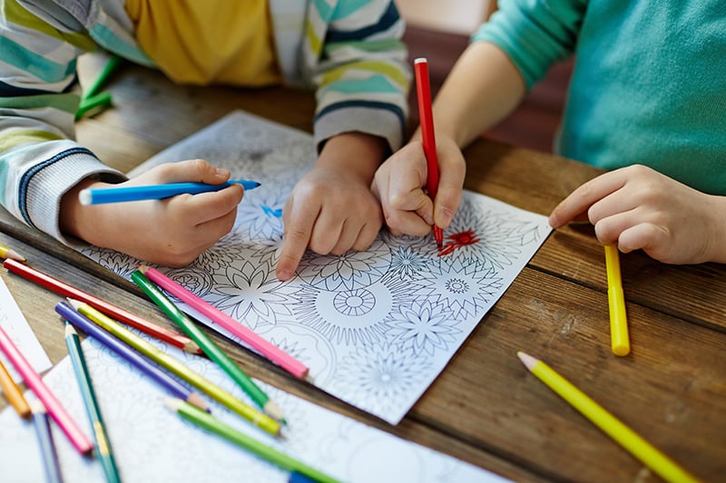 Kids coloring mandala with pencils of different colors