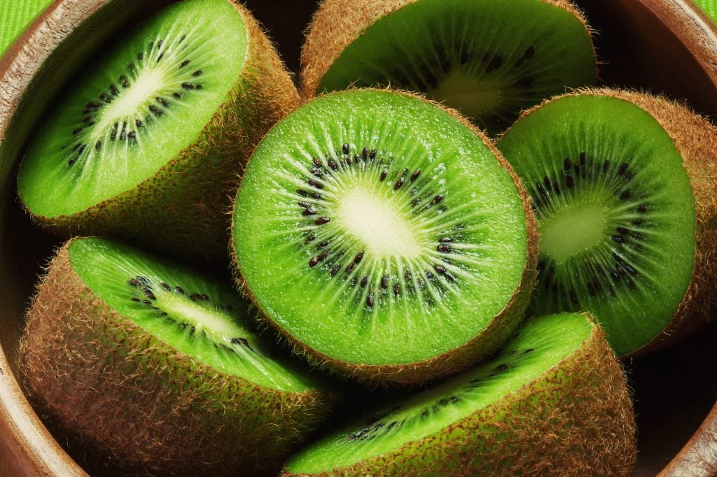 Top view of several half bright green kiwis in a wooden bowle