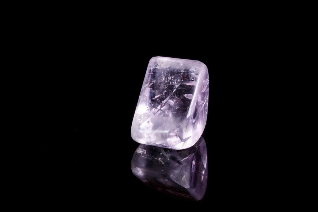 Close up of macro mineral stone spodumene in a light purple color on a black background